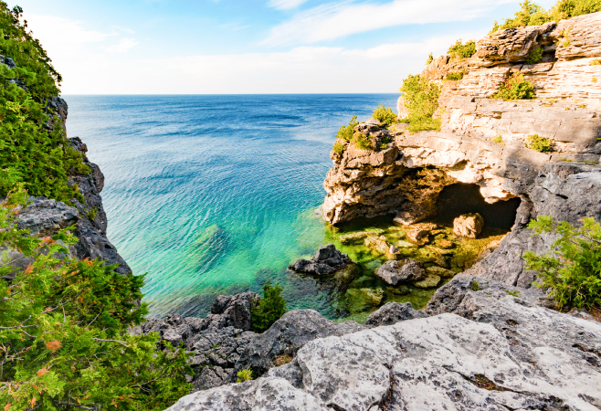 oneibccom2024 The Grotto is a popular attraction with a turquoise pool, dramatic caves, and limestone cliffs, located in Bruce Peninsula National Park.