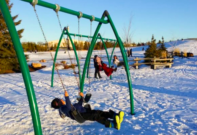 The park features a pavilion, spray park, climbing wall, playground, picnic sites, two fire rings with benches for campfires, and a small lake with a walking trail